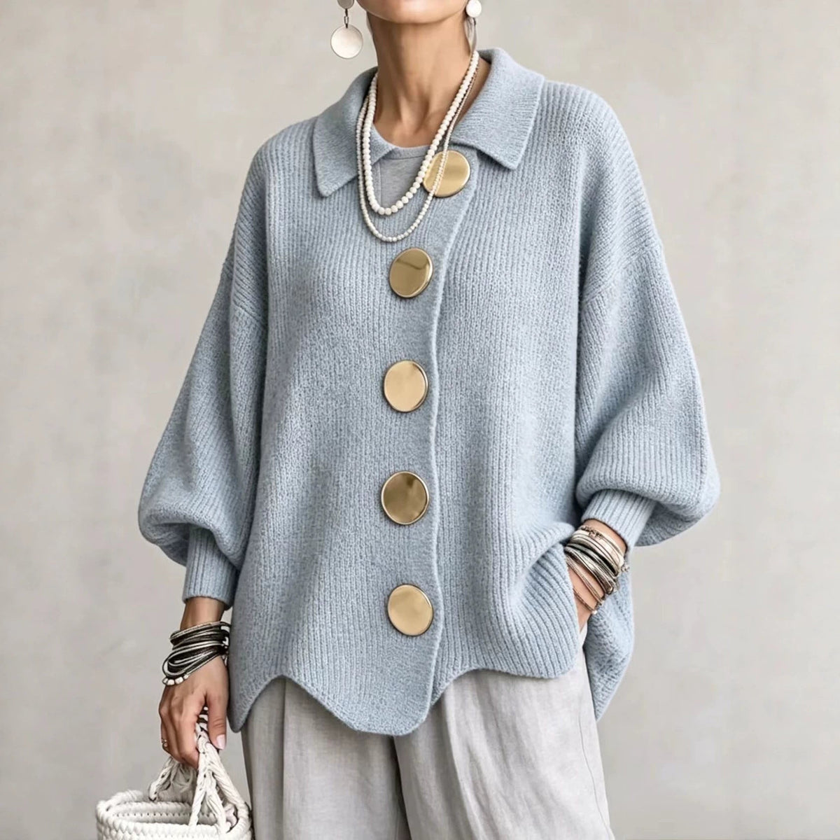A woman styling the sky blue collared sweater open over a simple dress for a layered look.