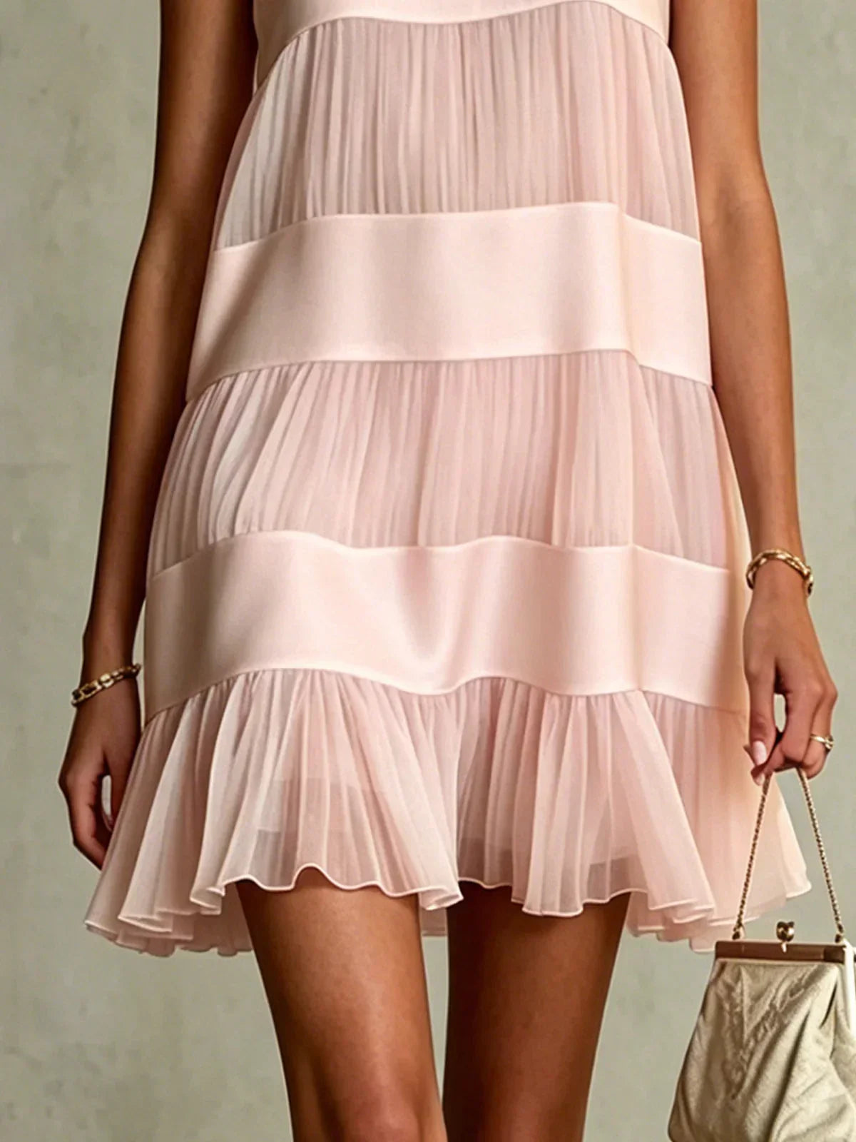 Model wearing the light pink layered mini dress while strolling outdoors, emphasizing its romantic movement and style.