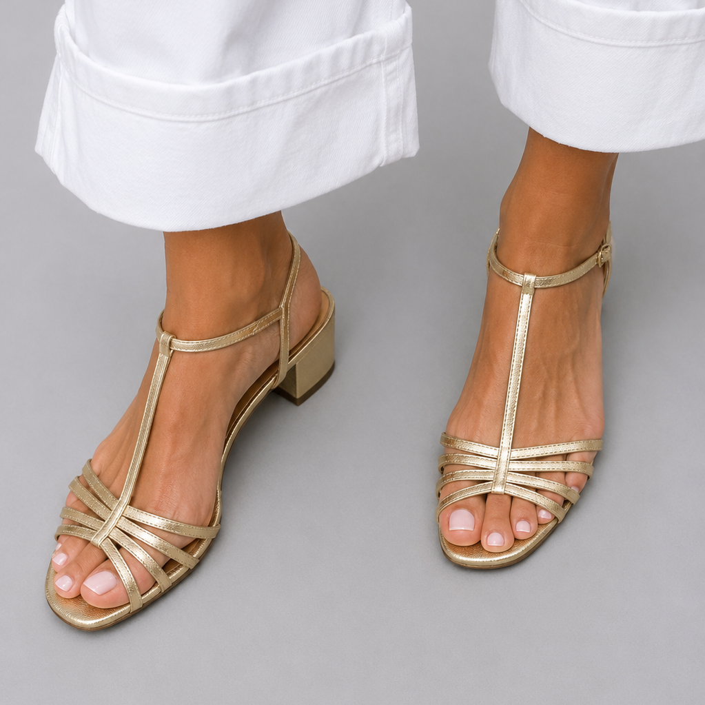 Pair of Allegra vintage sandals in gold color on a light background, top view.