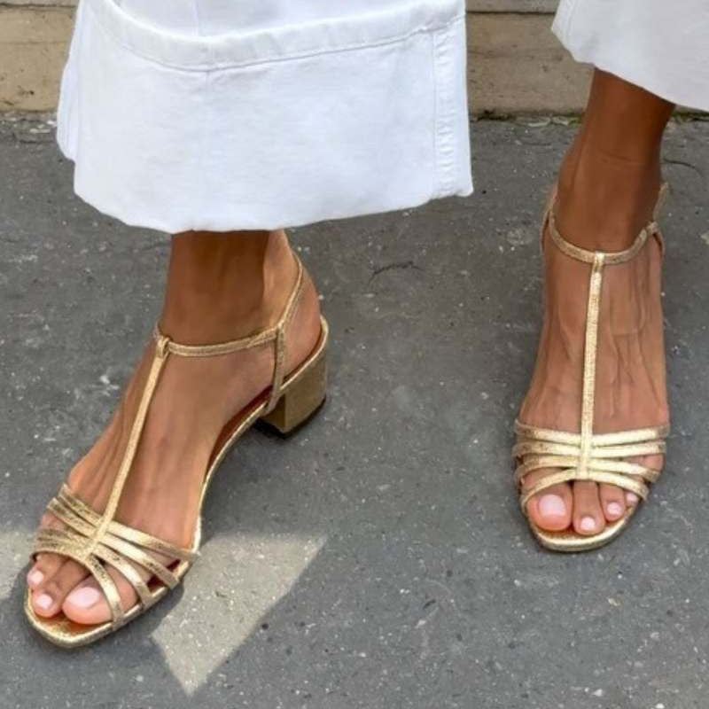Side profile of a woman wearing Allegra vintage sandals, walking on a paved path.