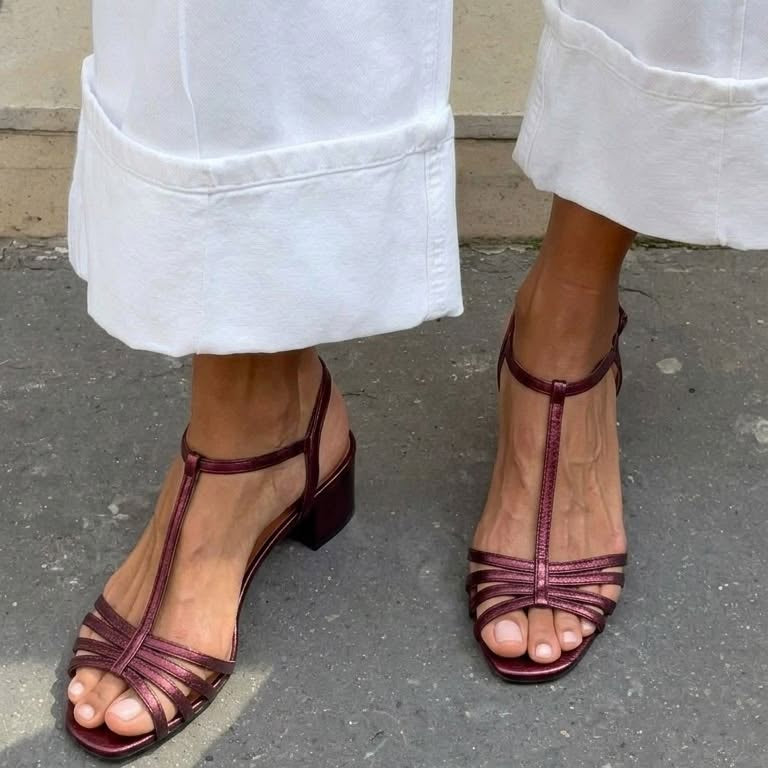Woman's feet wearing Allegra vintage sandals, relaxing in a garden setting.
