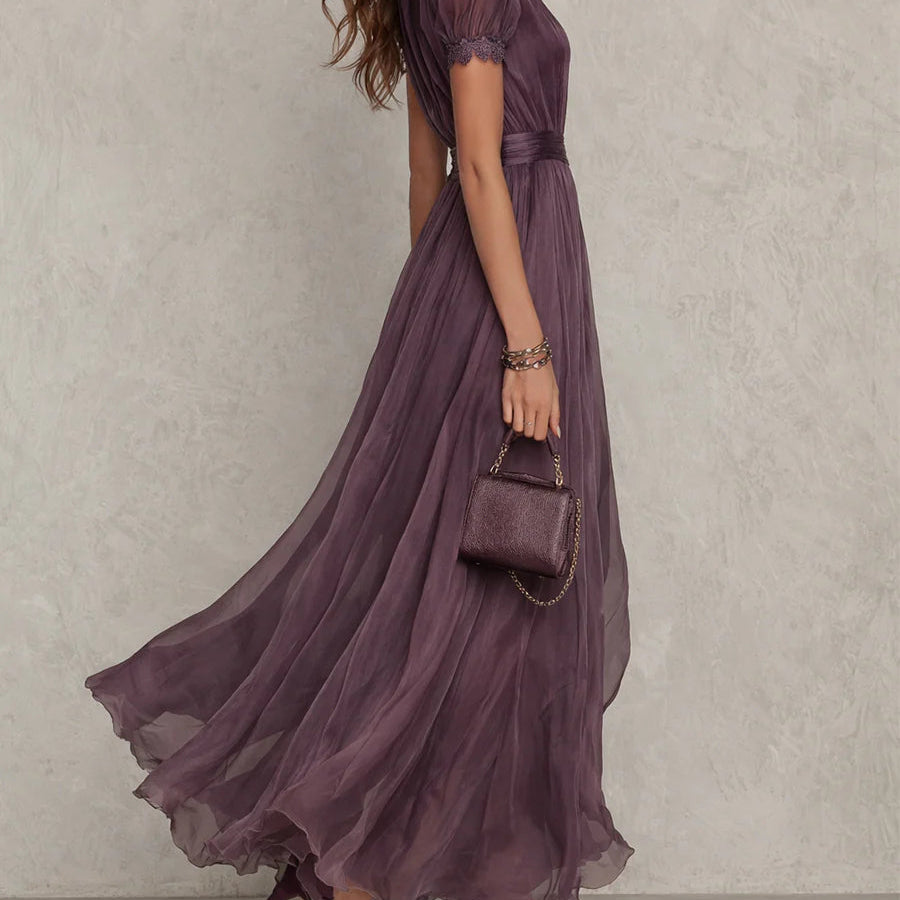 Side profile of the elegant purple chiffon maxi dress, highlighting the defined waist and delicate lace trim on the hem.
