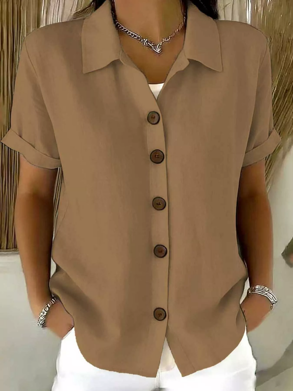 The brown button-up shirt draped on a hanger, emphasizing the soft, lightweight fabric texture.