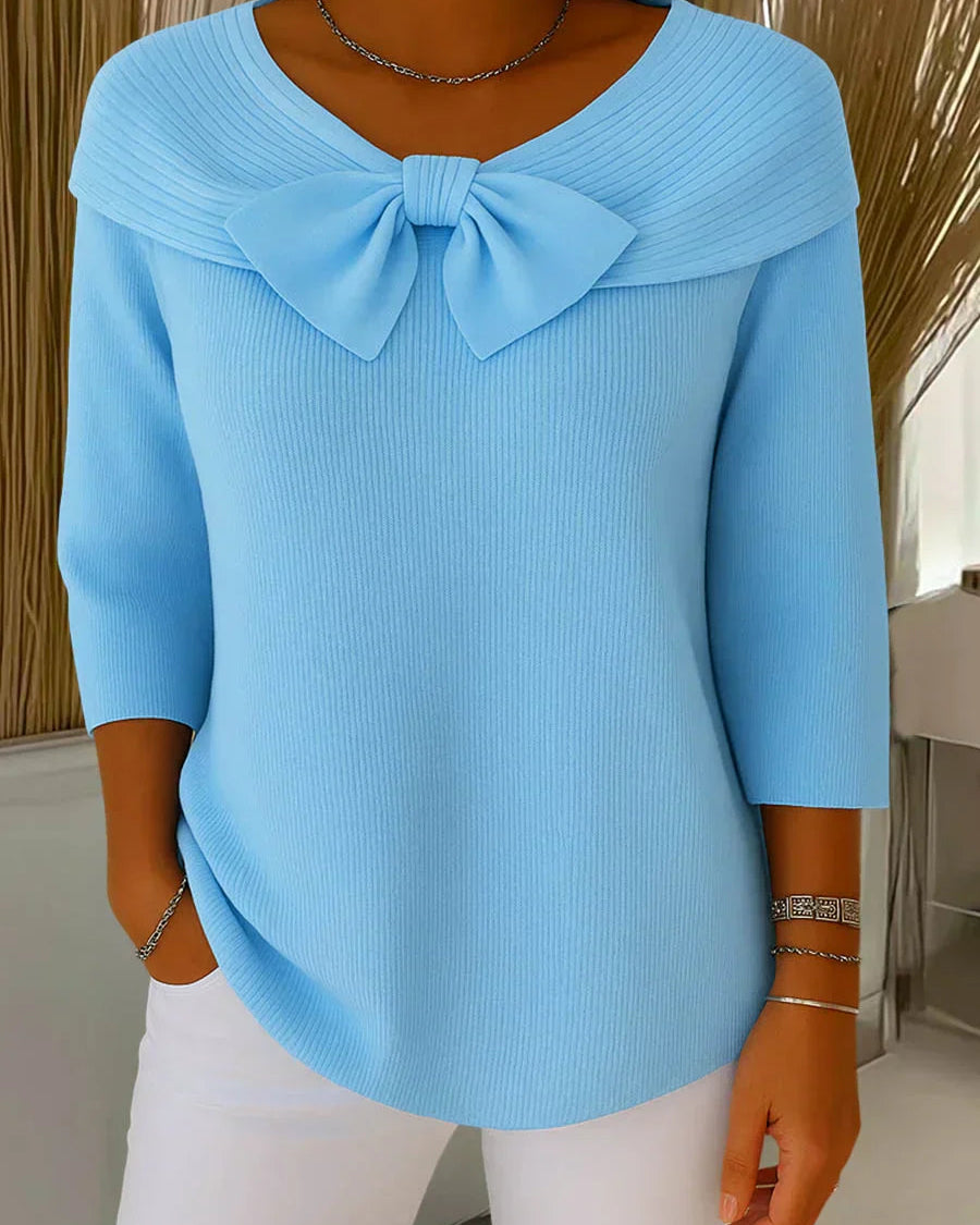 Front view of the Elara elegant knitted top in blue, showcasing the delicate bow detail and soft fabric texture.