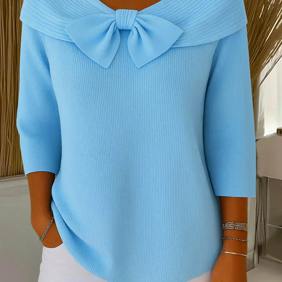 Front view of the Elara elegant knitted top in blue, showcasing the delicate bow detail and soft fabric texture.