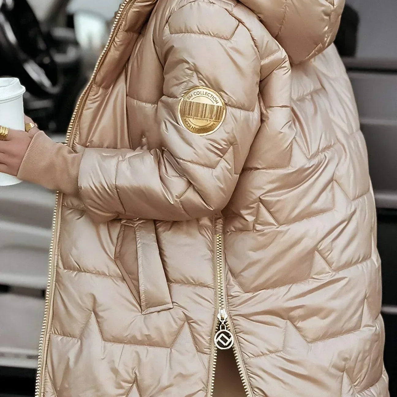 Woman zipping up a beige hooded winter jacket, showing the functional zipper and side pockets.