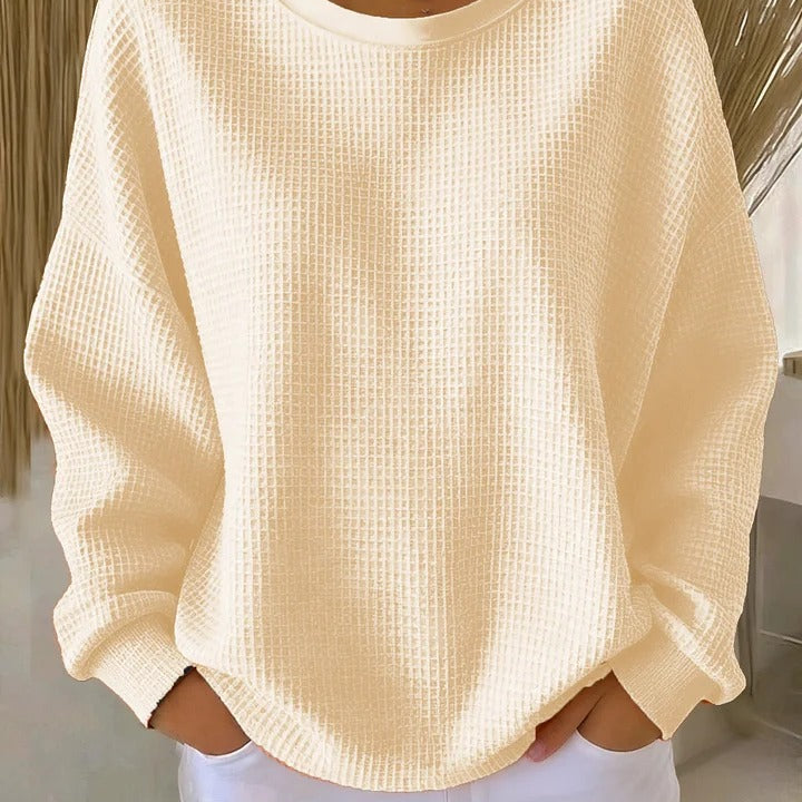 Woman comfortably seated, wearing the Soraya knitted wide collar sweater, demonstrating its everyday appeal.