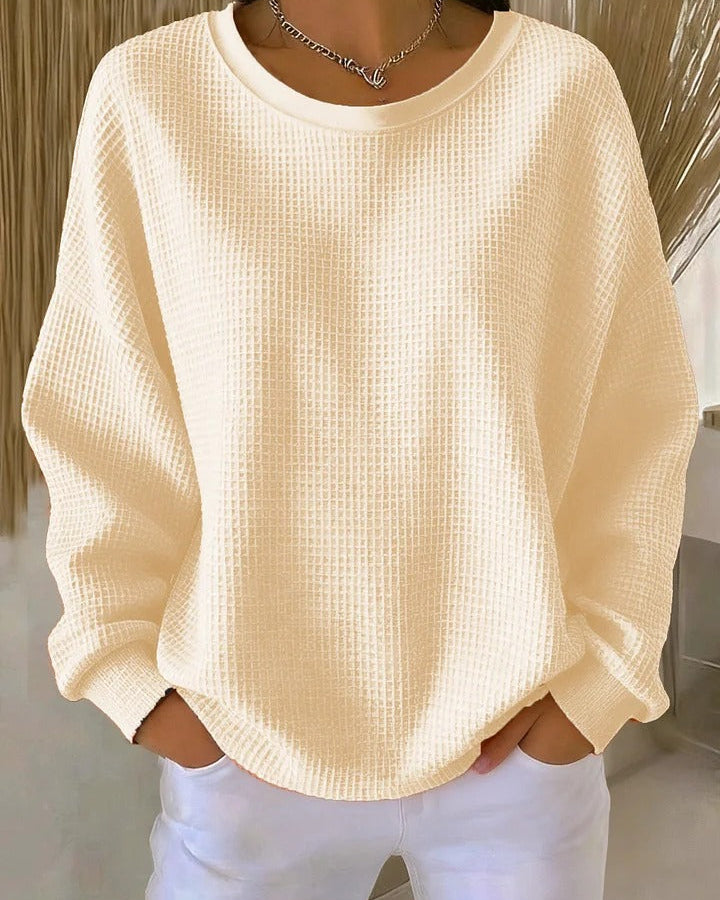Woman comfortably seated, wearing the Soraya knitted wide collar sweater, demonstrating its everyday appeal.