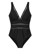 Model walking on a beach in the navy one-piece, showcasing movement and versatility of the swimwear.