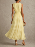 Side profile of a woman wearing the sleeveless maxi dress, demonstrating the flattering fit and graceful drape of the skirt.