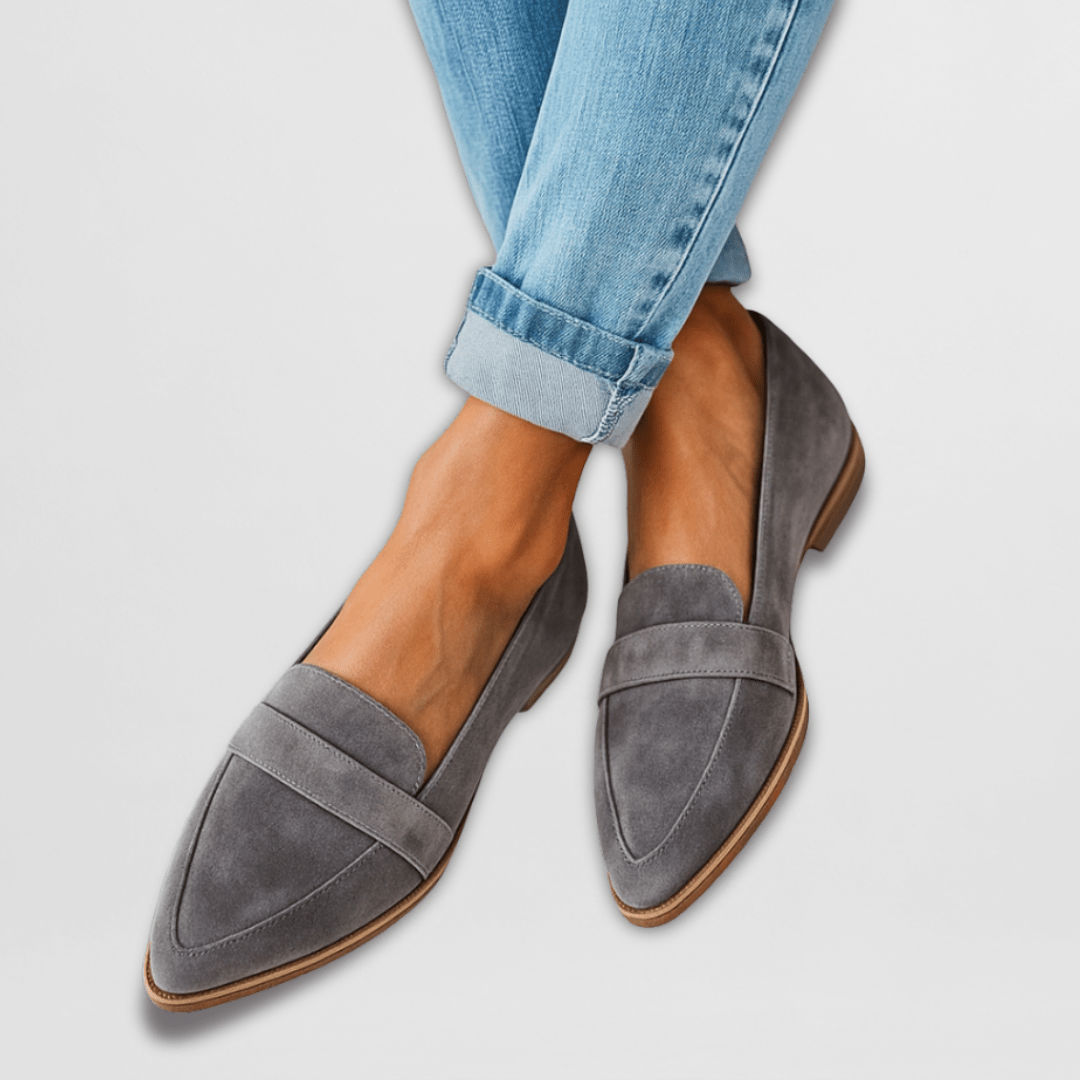 Side profile of a woman wearing black suede loafers, showcasing the subtle low wedge heel and sleek design.