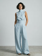 Lifestyle shot of women's wide-leg trousers worn casually with flat sandals for a relaxed summer look.