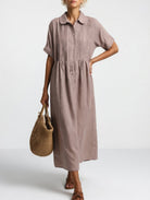 Detail shot of the wide short sleeves and button placket on a blue relaxed cotton shirt dress.