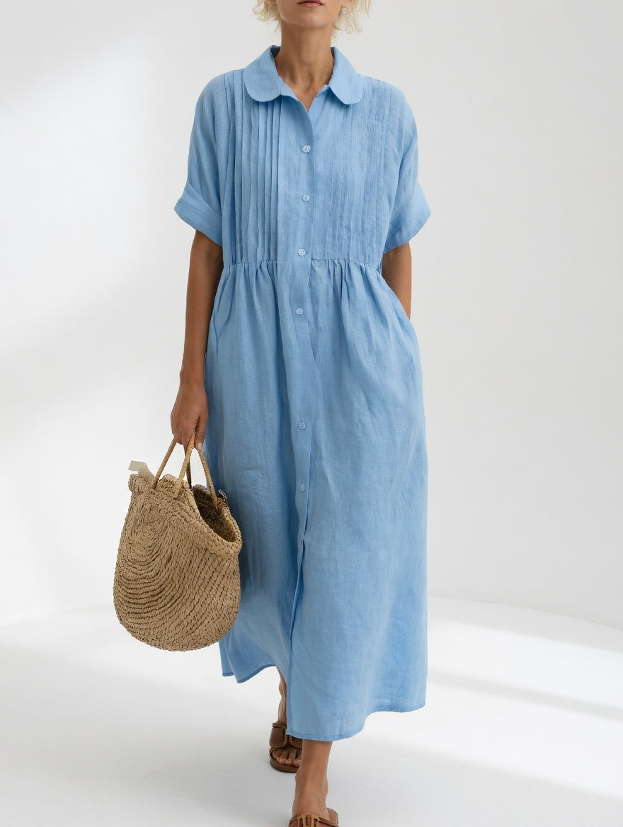 Model wearing a white relaxed cotton shirt dress, captured in a natural setting, emphasizing its timeless style.