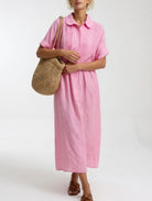 Side profile of a model in a pink relaxed shirt dress, demonstrating the loose cut with structured waist.