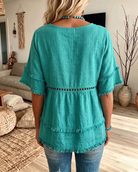 Close-up of the flattering V-neckline on a white casual blouse, highlighting its soft textured fabric.
