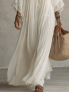 Model walking on a beach at sunset, elegantly styled in the versatile Ianthe lace V-neck maxi dress.