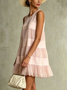 Detailed view of the sleeveless round neckline and delicate satin patchwork on this charming pink mini dress.