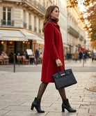 Side profile of a woman wearing the Alessia classic coat, demonstrating its comfortable fit and graceful drape in a city setting.
