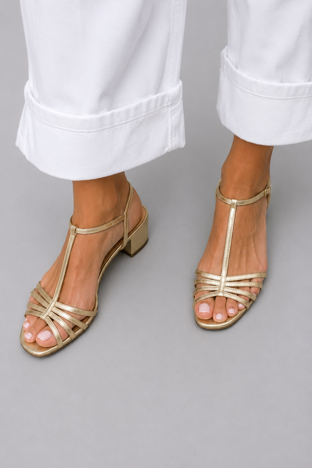 Pair of Allegra vintage sandals in gold color on a light background, top view.