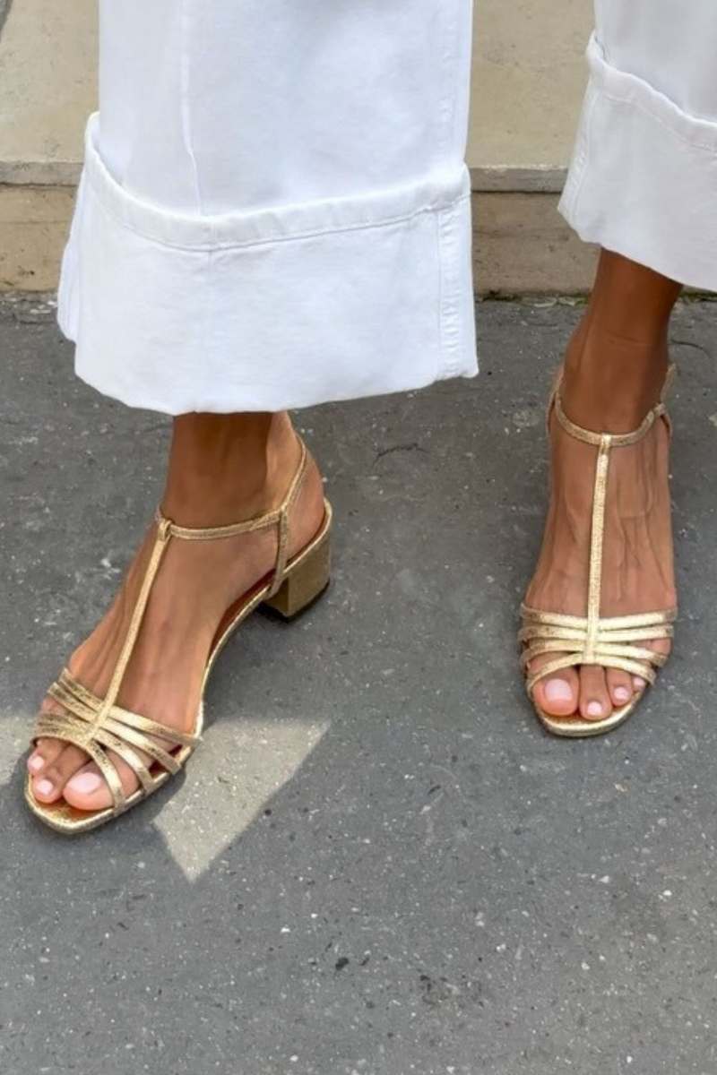 Side profile of a woman wearing Allegra vintage sandals, walking on a paved path.
