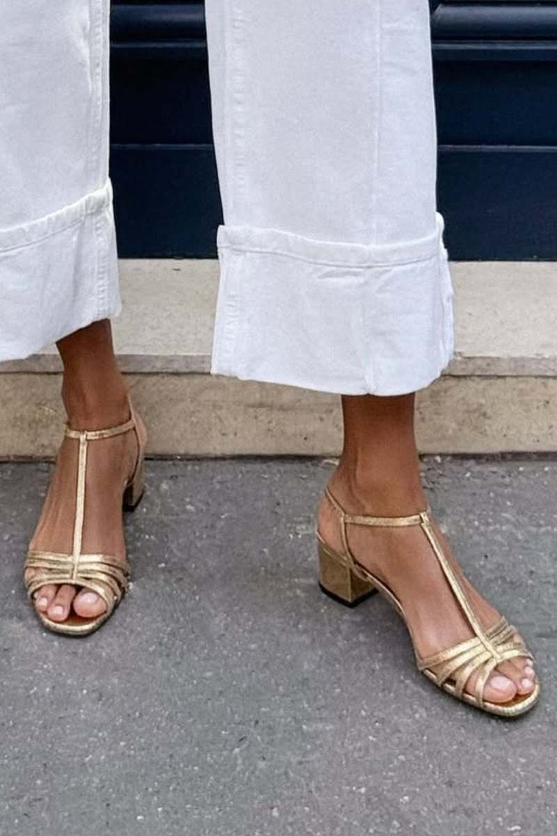 Close-up of the golden detail and strap design of the Allegra vintage sandals.