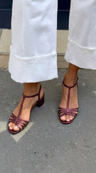 Woman's feet wearing Allegra vintage sandals, relaxing in a garden setting.