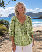 Green Fiona blouse on a hanger, presenting the full design and vibrant color.