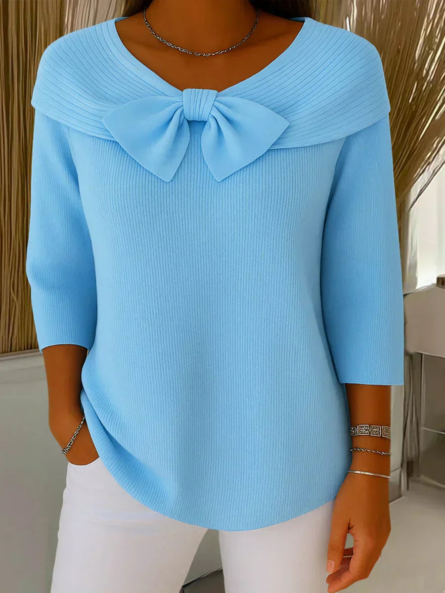 Front view of the Elara elegant knitted top in blue, showcasing the delicate bow detail and soft fabric texture.