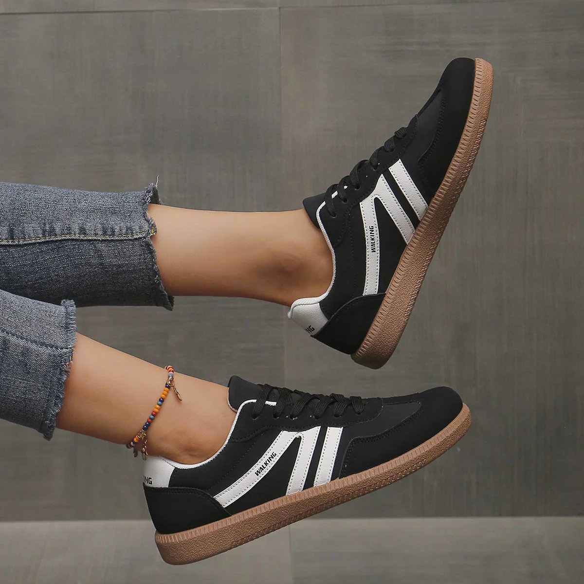 A single black Elara orthopaedic cushioned trainer, presented in a minimalist studio setting, side view.