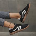 A single black Elara orthopaedic cushioned trainer, presented in a minimalist studio setting, side view.