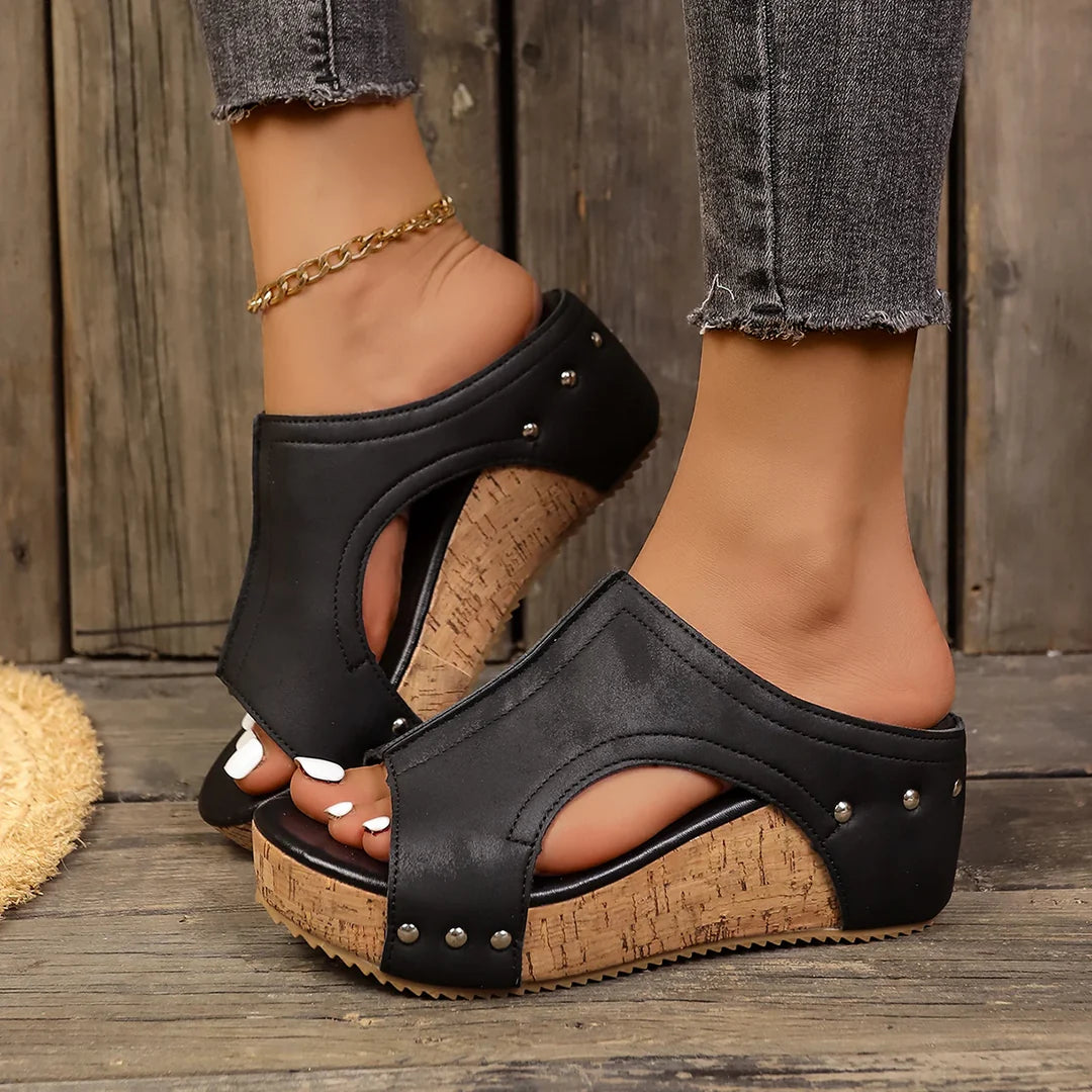 Elysia studded platform wedges in classic black, showcasing the elegant studded strap design from a front angle.