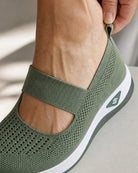 Close-up of the heel tab and elastic strap while stepping into the green Carry shoe