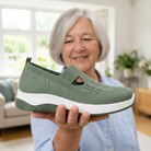 A woman holding the green Carry orthopaedic slip-on flat on her open hand