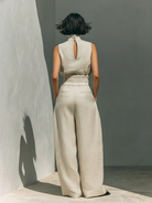 Model wearing beige wide-leg trousers, demonstrating a comfortable and elegant fit from a standing pose.