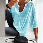 Close-up of the delicate crochet work on the sleeve and neckline of a light, flowing blouse.