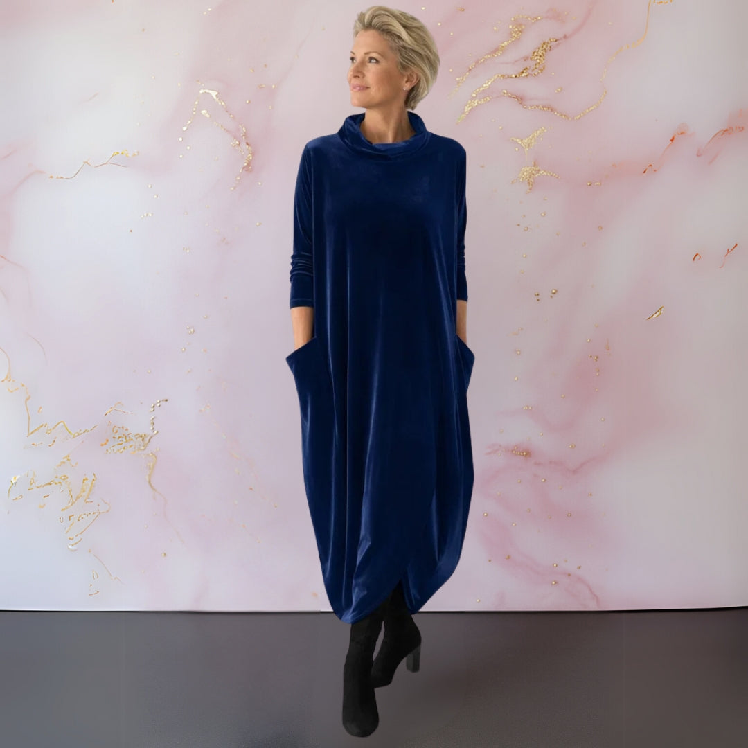 A side profile of the woman in the blue Katiya velvet maxi dress, highlighting the flowing fabric and discreet side pocket.