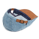 A stack of Kian classic denim flat caps in various shades of blue, emphasizing color options.