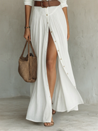Side profile of a woman wearing a black Linnea linen blend maxi dress, highlighting the pleated skirt movement.