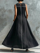 Model wearing a flowing burgundy maxi dress, showcasing the wide skirt and side pockets in a relaxed pose.