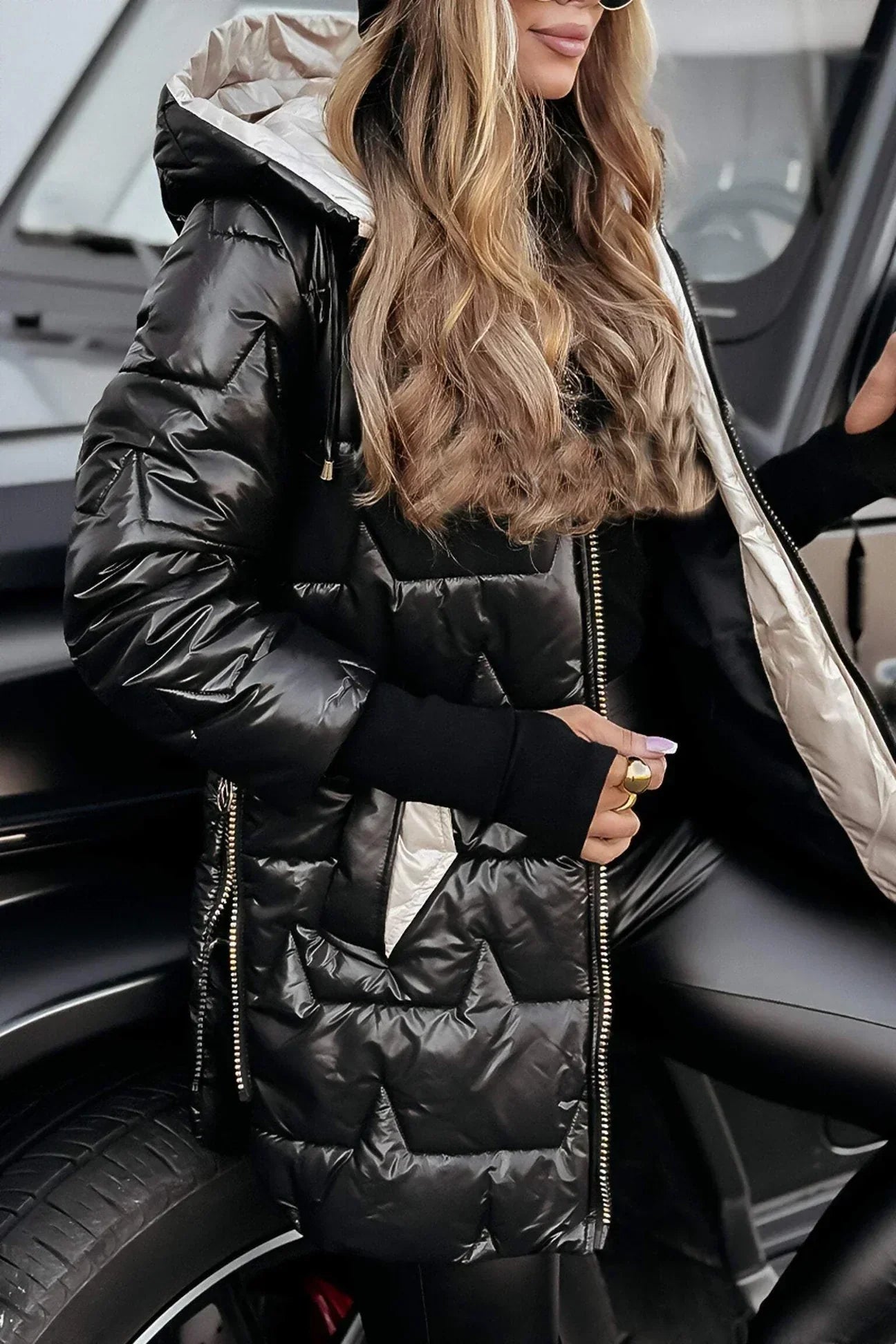 Lifestyle shot of a woman walking outdoors in a gray hooded winter jacket, illustrating its practical use.