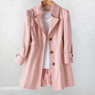 A woman confidently walking outdoors wearing the Renata summer trench coat in khaki, showcasing its relaxed silhouette.