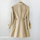 A woman sitting casually, wearing the Renata summer trench coat, illustrating its comfort and versatility for everyday wear.