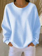 Front view of a woman wearing the Soraya knitted wide collar sweater in a light color, showcasing its loose fit.
