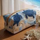 A medium Soraya quilted cosmetic bag, showcasing the intricate blue shells pattern from a top-down perspective, ideal for travel.