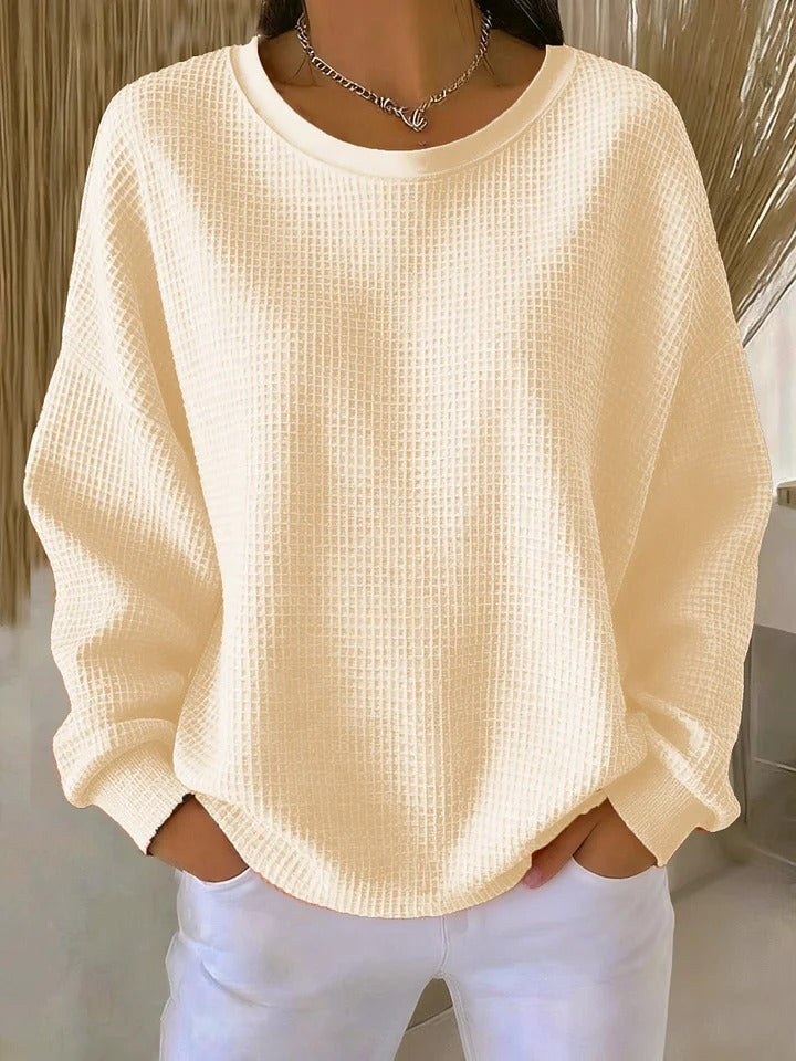 Woman comfortably seated, wearing the Soraya knitted wide collar sweater, demonstrating its everyday appeal.