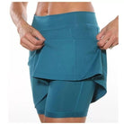 Full length view of a woman posing confidently in a purple active skort, highlighting its style.