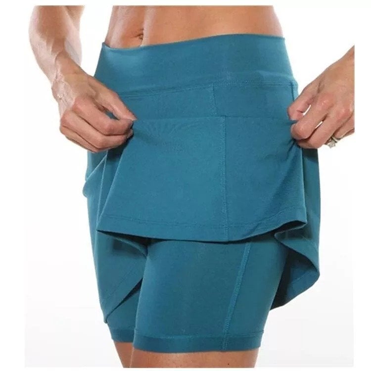 Full length view of a woman posing confidently in a purple active skort, highlighting its style.